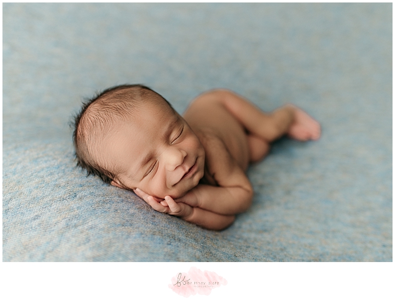 Newborn baby boy side laying smiling