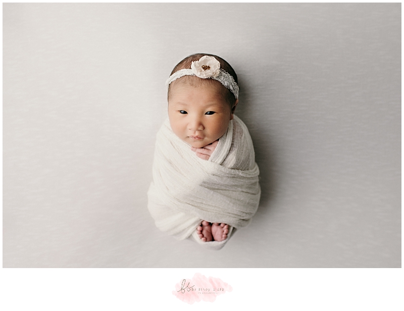 Calgary newborn photo baby girl in toes peeking out pose with eyes open