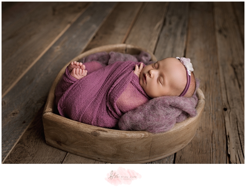 Calgary Newborn Photographer laying in heart wooden bowl in purple